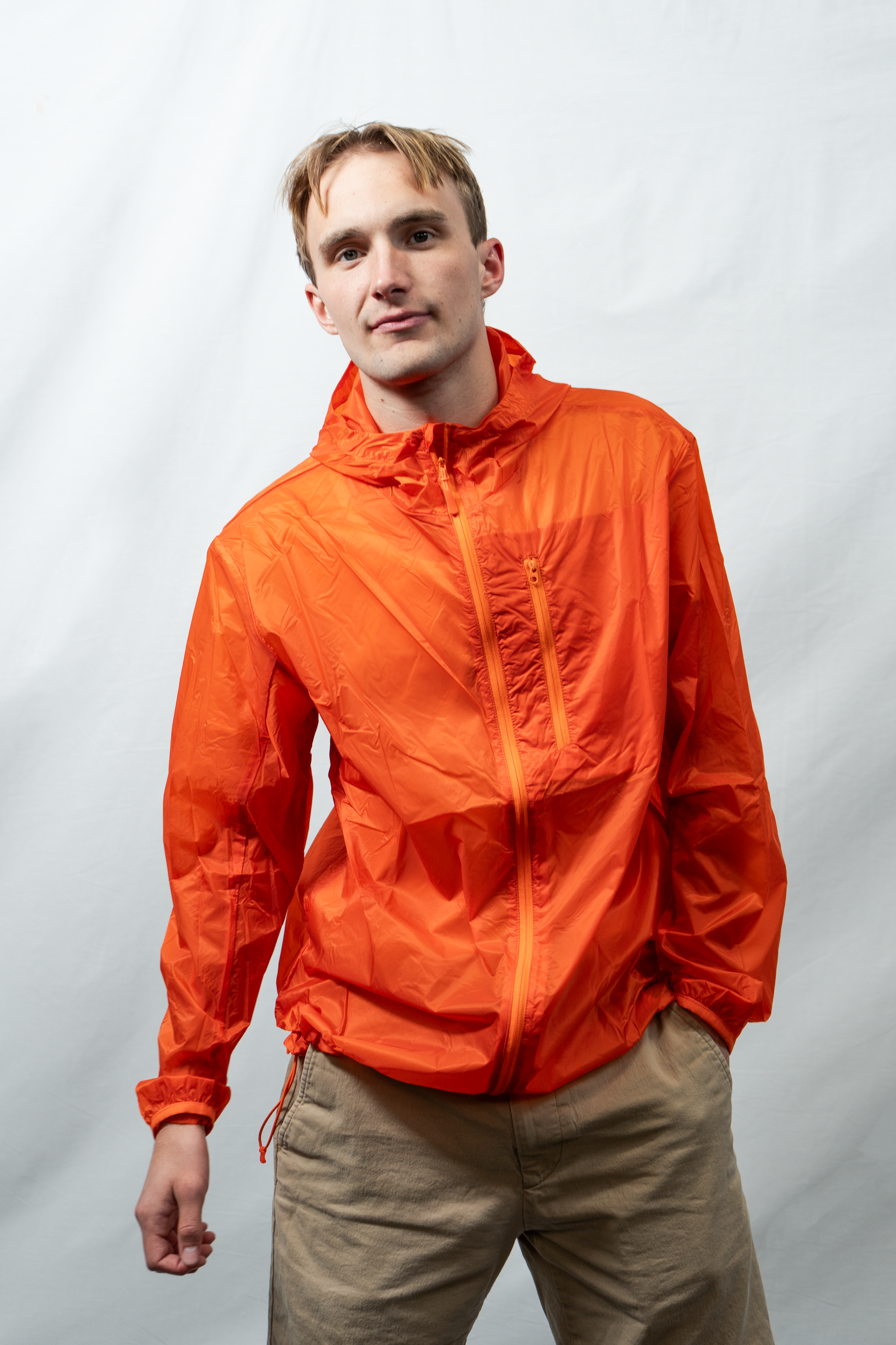 Man wearing an orange jacket against a plain background