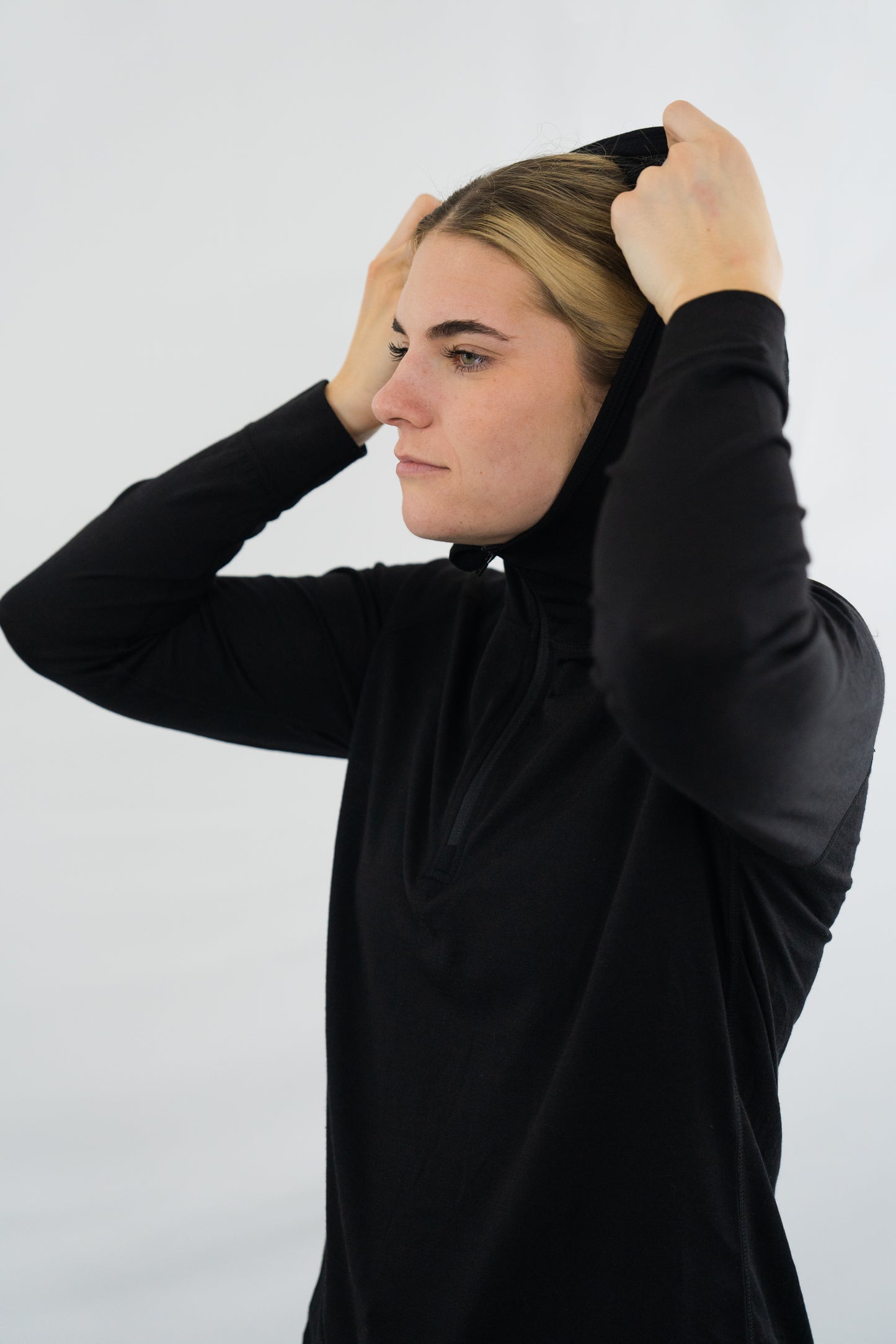 Person wearing womens black wool base layer hoodie with hood on from Squak Mountain Co.