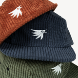 Three ribbed corduroy flat-brim hats stacked together, showing Canyon Amber, Midnight Blue, and Evergreen Pine colors, each with a white embroidered bird logo on the front.